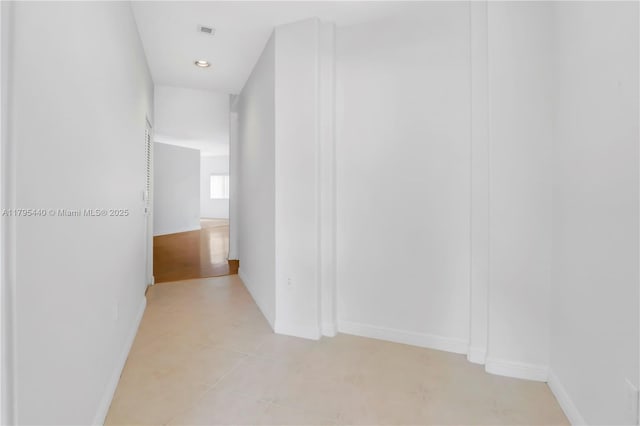 corridor featuring light tile patterned floors, baseboards, and visible vents