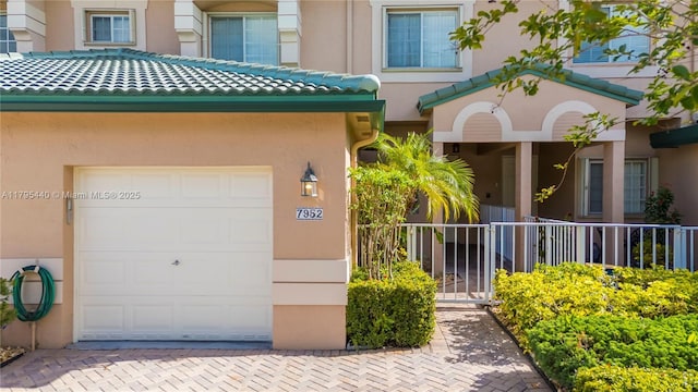 property entrance featuring stucco siding, driveway, and a garage