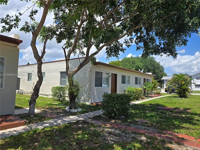view of front of house with stucco siding and a front lawn