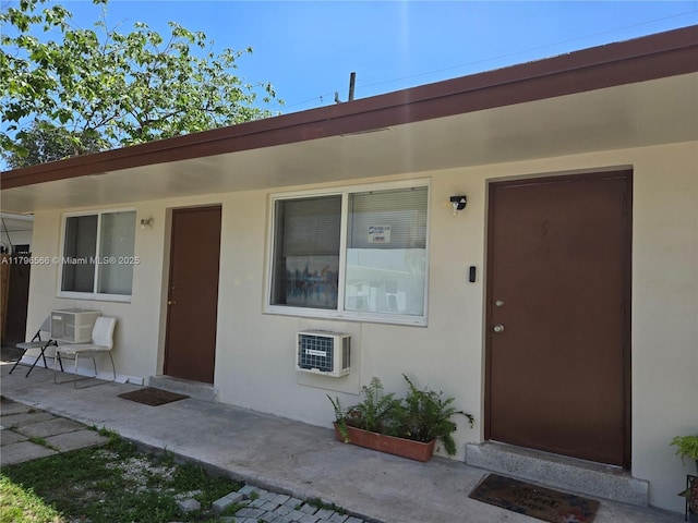 entrance to property with heating unit and stucco siding