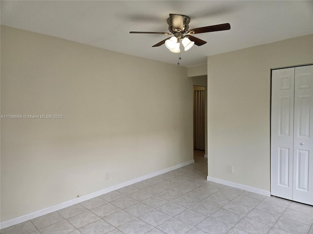 unfurnished bedroom featuring light tile patterned flooring, a closet, baseboards, and a ceiling fan