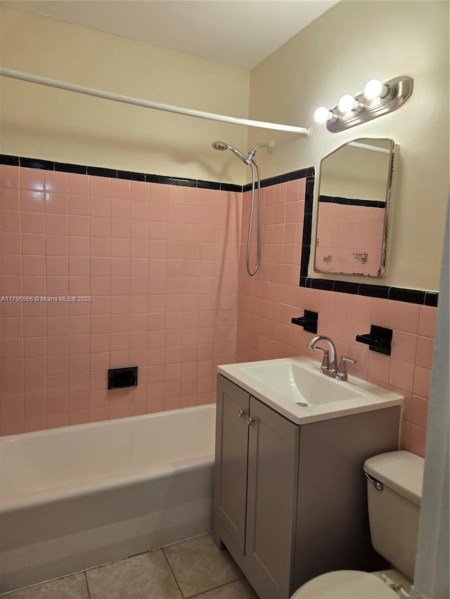 bathroom featuring tile walls, toilet, vanity, tile patterned floors, and tub / shower combination