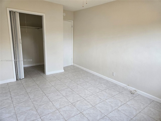 unfurnished bedroom featuring a closet, light tile patterned floors, and baseboards