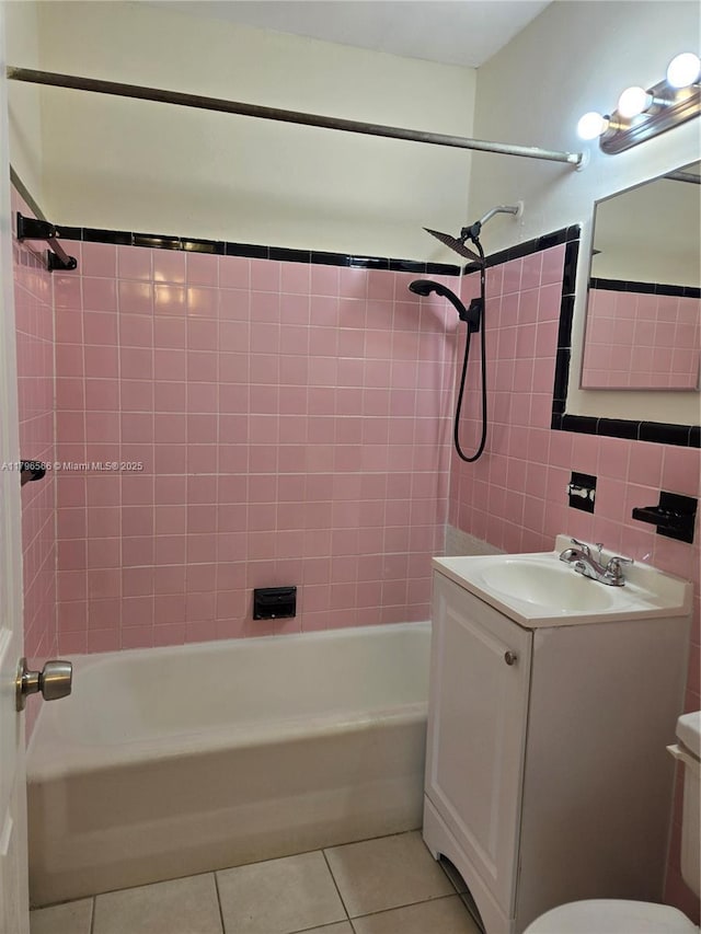 bathroom featuring toilet, shower / bath combination, tile patterned floors, tile walls, and vanity