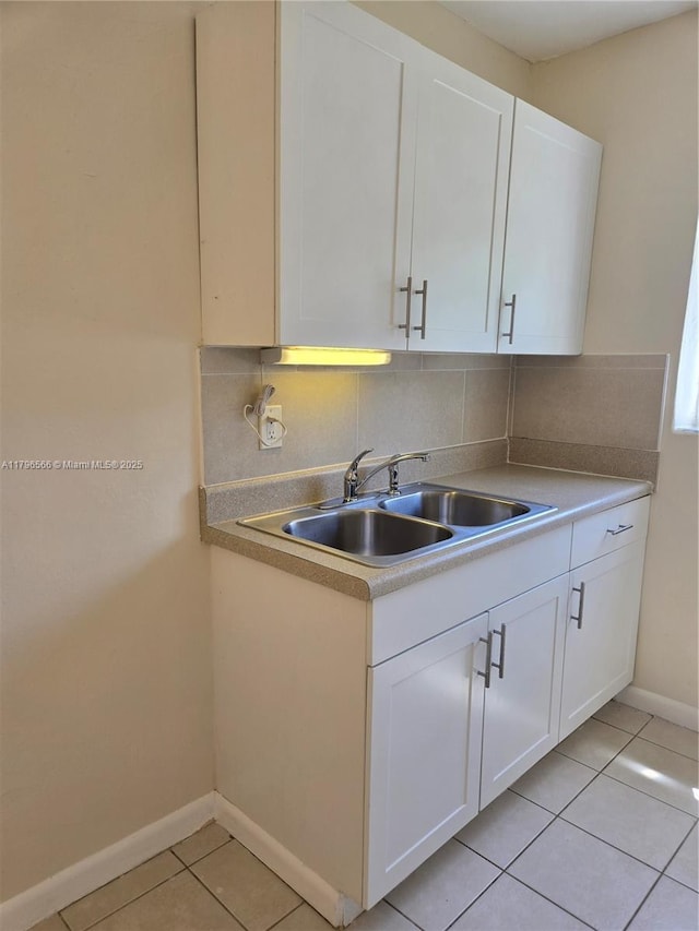kitchen featuring a sink, light tile patterned flooring, tasteful backsplash, and baseboards