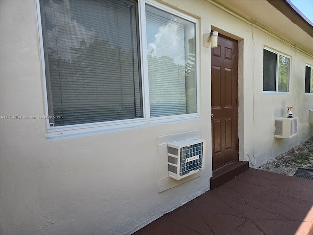 view of side of home featuring stucco siding and an AC wall unit