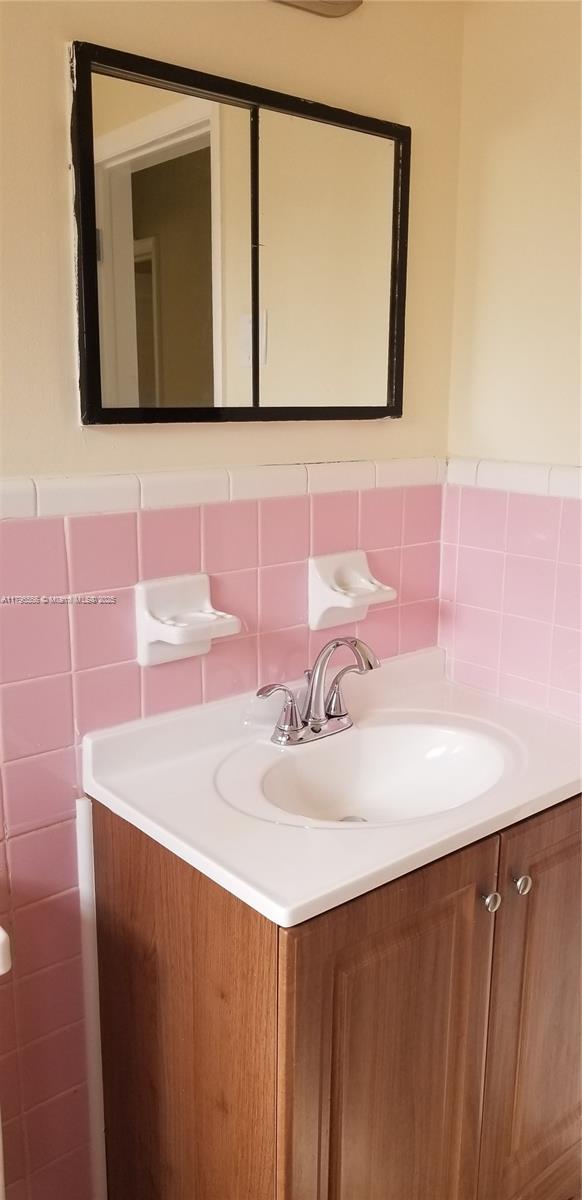 bathroom featuring vanity and tile walls