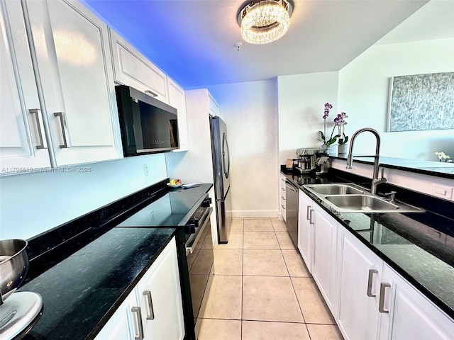 kitchen featuring light tile patterned floors, a sink, stainless steel appliances, white cabinetry, and baseboards
