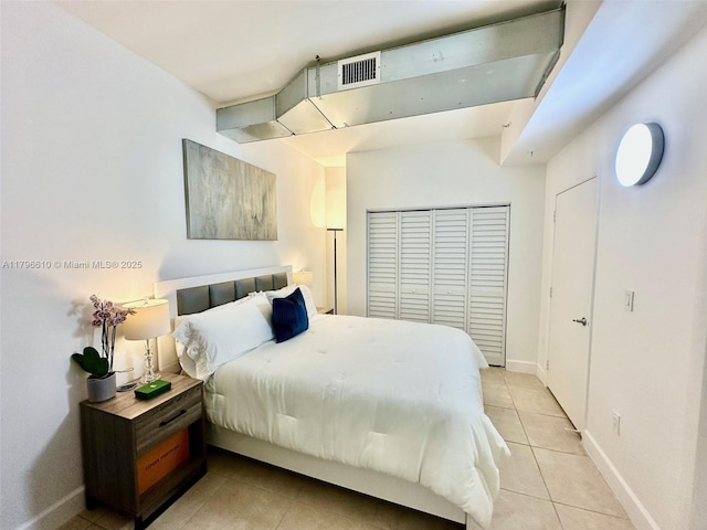 bedroom featuring a closet, light tile patterned floors, visible vents, and baseboards