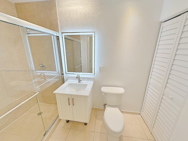bathroom featuring toilet, a closet, tile patterned flooring, a shower stall, and vanity