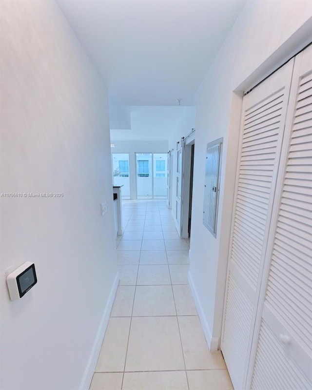 hallway with electric panel, baseboards, and light tile patterned floors