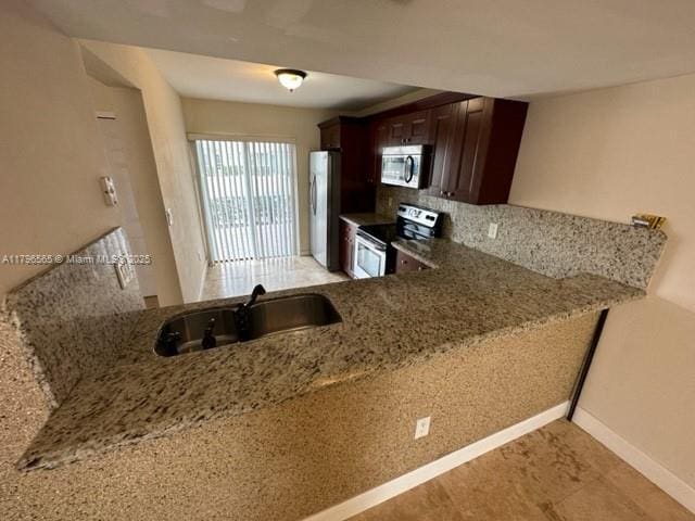 kitchen with light stone countertops, dark brown cabinets, a sink, decorative backsplash, and stainless steel appliances