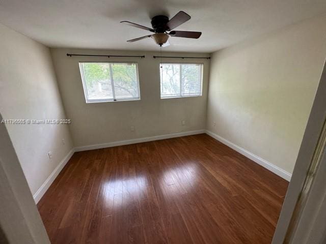 empty room featuring wood finished floors, baseboards, and ceiling fan