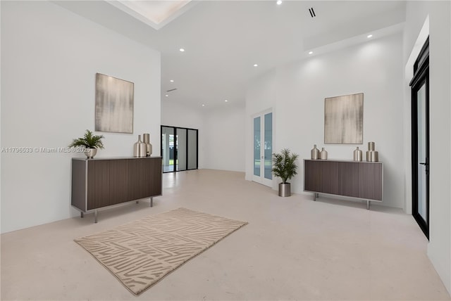 corridor with concrete floors, recessed lighting, and a high ceiling