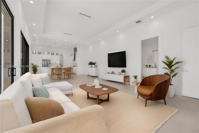 living area featuring visible vents, a high ceiling, and recessed lighting