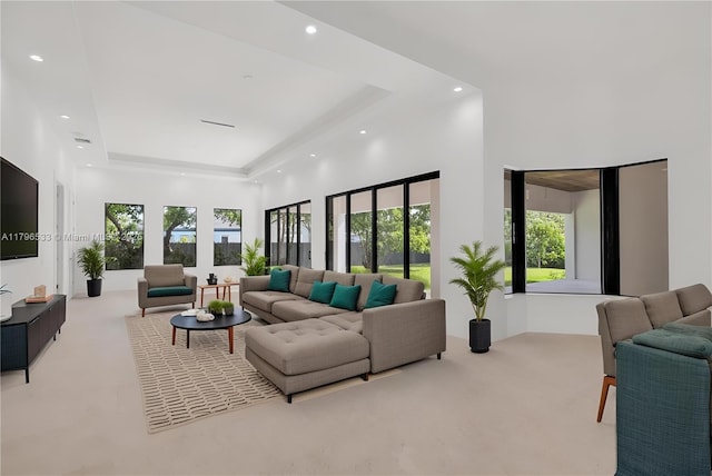 carpeted living room featuring a raised ceiling, a towering ceiling, and recessed lighting