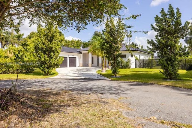 view of front of house featuring a front lawn, driveway, a garage, and fence