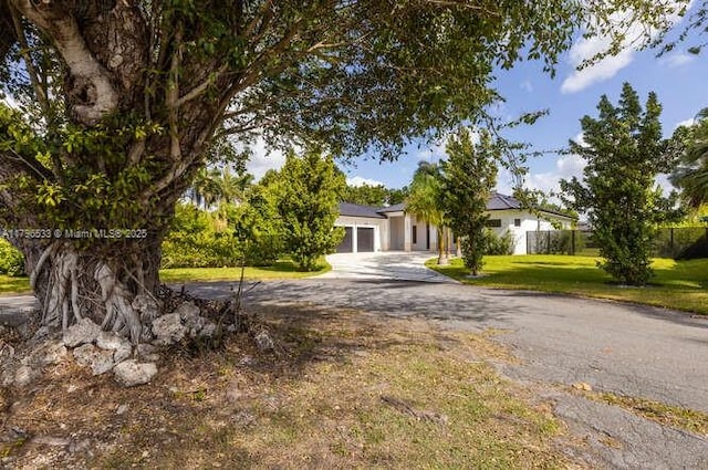 obstructed view of property with a front lawn, driveway, and an attached garage