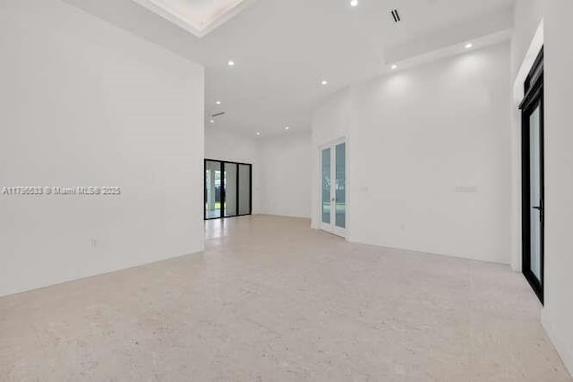empty room featuring visible vents, recessed lighting, and a towering ceiling