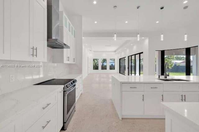 kitchen featuring wall chimney range hood, plenty of natural light, stainless steel electric range, and a sink