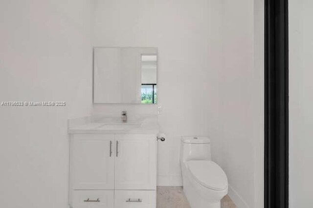 bathroom with toilet, baseboards, and vanity