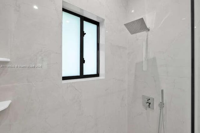 bathroom with a tile shower and a healthy amount of sunlight
