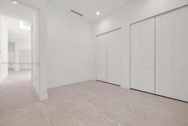 unfurnished bedroom with recessed lighting, visible vents, and two closets