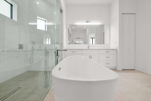 bathroom featuring walk in shower, a soaking tub, and vanity