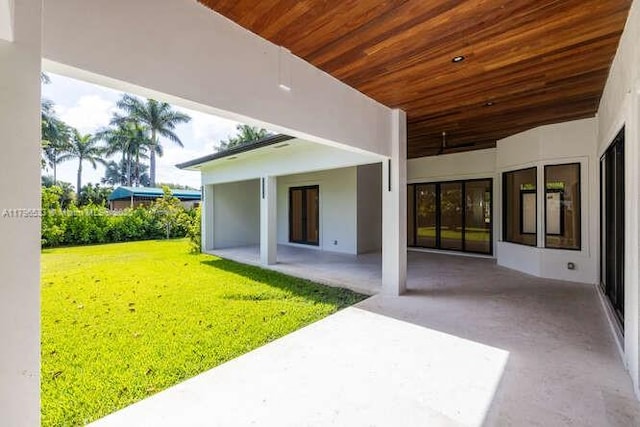 back of house with a yard, a patio area, and stucco siding