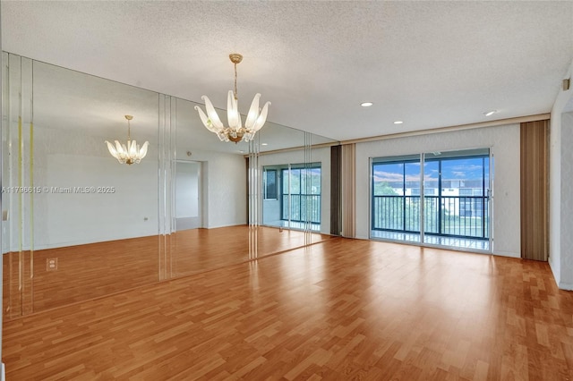 spare room featuring recessed lighting, a textured ceiling, wood finished floors, and a notable chandelier