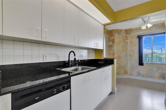kitchen with a sink, white cabinetry, dark stone counters, and dishwasher