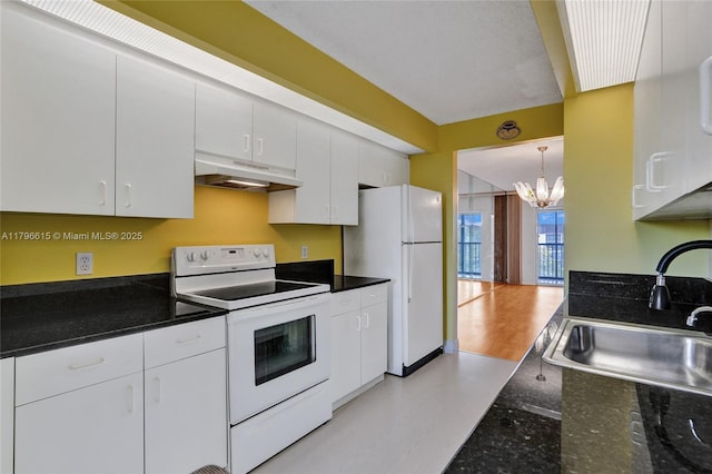 kitchen with under cabinet range hood, a chandelier, white appliances, and white cabinetry