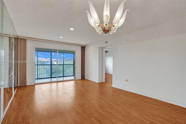 empty room featuring a notable chandelier, recessed lighting, a textured ceiling, baseboards, and light wood-type flooring
