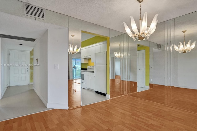 interior space with a textured ceiling, visible vents, light wood-style flooring, and a notable chandelier