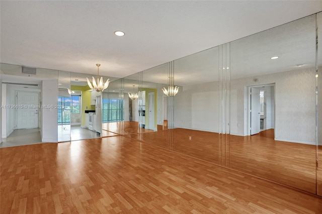 unfurnished room with light wood finished floors, a chandelier, visible vents, and recessed lighting