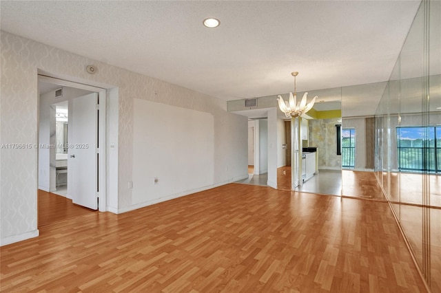 interior space featuring a notable chandelier, baseboards, visible vents, and light wood-style floors
