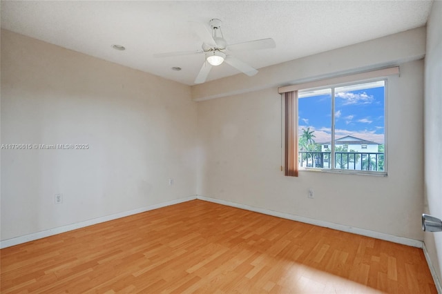 spare room with ceiling fan, light wood-style flooring, and baseboards