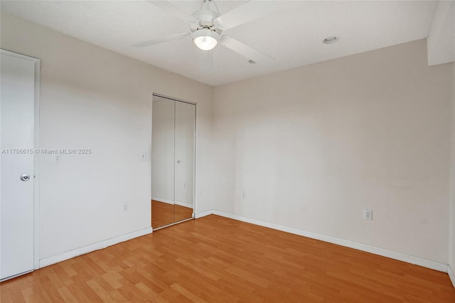 unfurnished bedroom featuring ceiling fan, light wood-style flooring, and baseboards