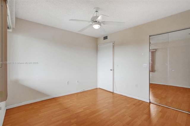 unfurnished bedroom featuring wood finished floors, a closet, visible vents, baseboards, and ceiling fan