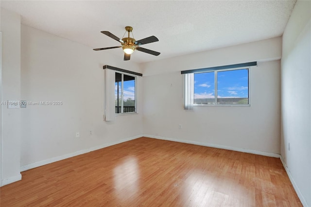 empty room featuring light wood finished floors, baseboards, and a ceiling fan