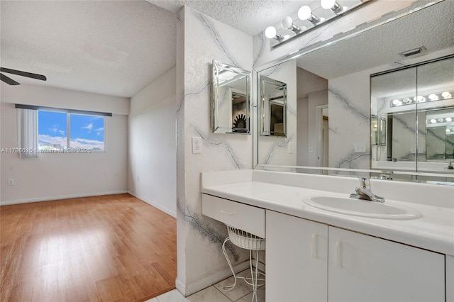 bathroom featuring wood finished floors, a textured ceiling, visible vents, ceiling fan, and vanity
