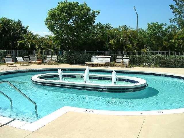 community pool featuring a hot tub, fence, and a patio