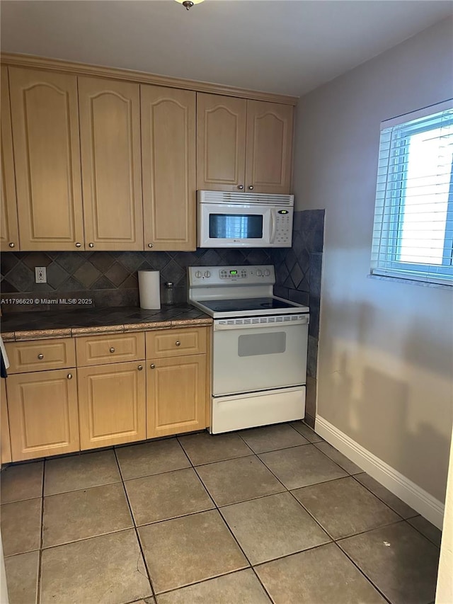kitchen with white appliances, tile patterned flooring, decorative backsplash, baseboards, and dark countertops