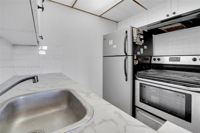 kitchen featuring under cabinet range hood, a sink, decorative backsplash, stainless steel appliances, and white cabinets