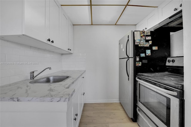 kitchen featuring a sink, light wood-type flooring, white cabinetry, backsplash, and stainless steel electric range oven