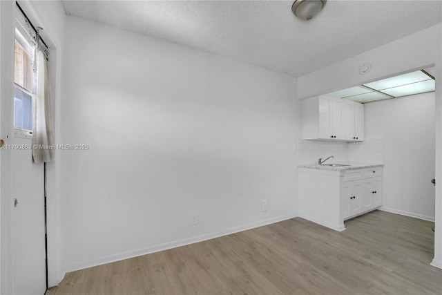 laundry room with light wood finished floors, baseboards, and a sink