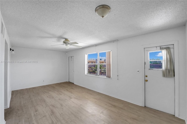 spare room featuring ceiling fan, light wood finished floors, and plenty of natural light