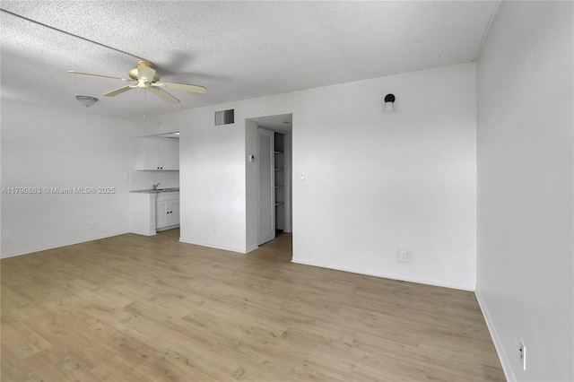 unfurnished room featuring light wood-type flooring, visible vents, ceiling fan, and a textured ceiling