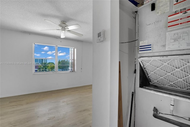 interior space featuring ceiling fan, a textured ceiling, baseboards, and light wood finished floors