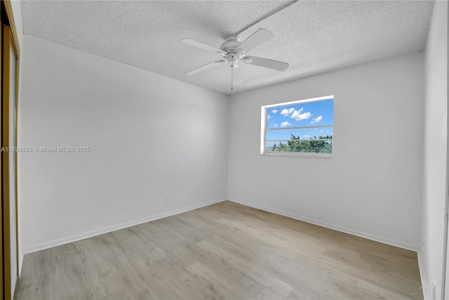 unfurnished room with ceiling fan, a textured ceiling, baseboards, and wood finished floors